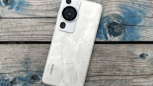 White smartphone with unique texture placed on weathered wood background.