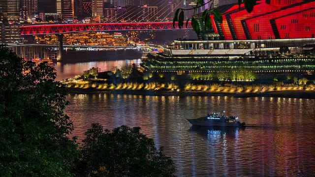 A stunning nighttime cityscape featuring a vibrant illuminated bridge and a reflective river scene.