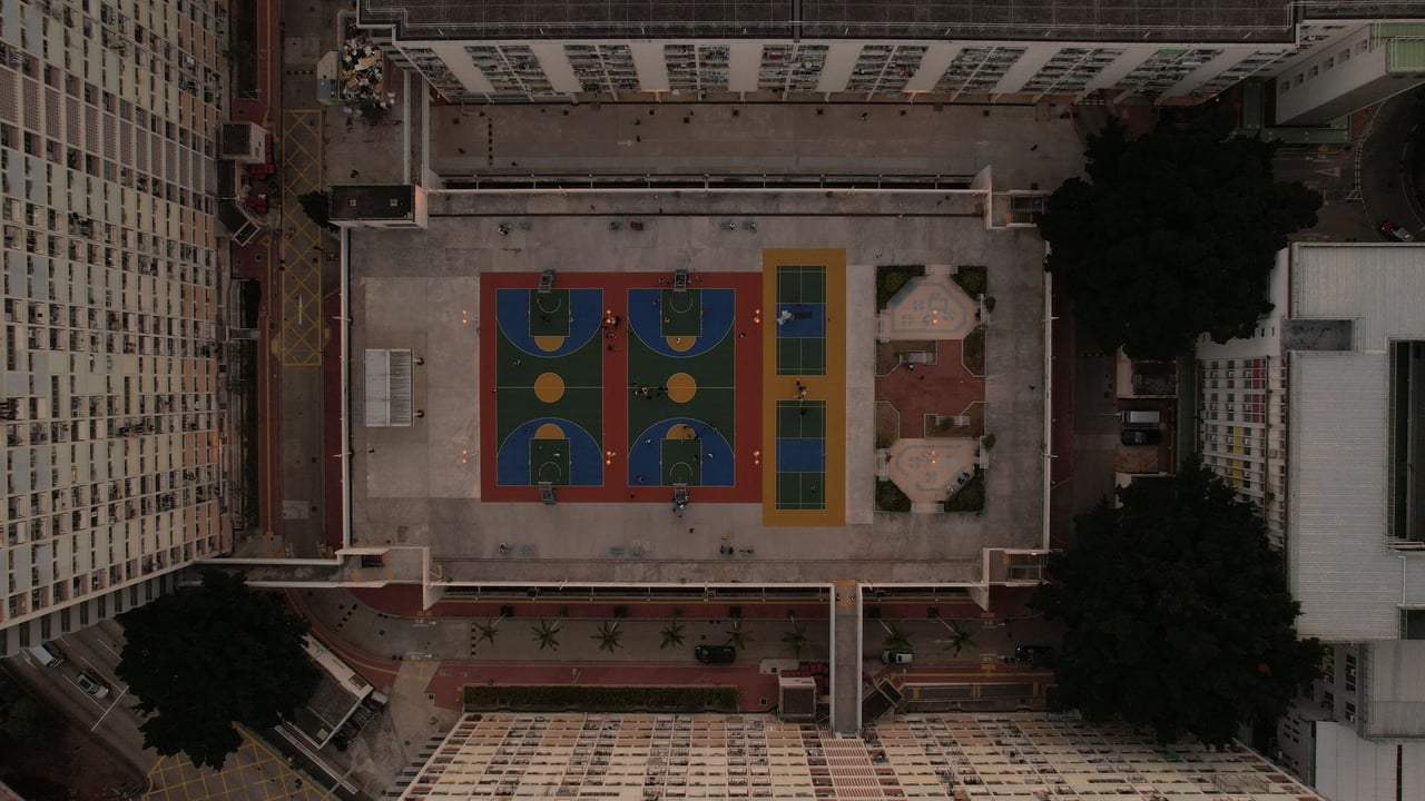 Drone shot of colorful basketball courts in Kowloon's urban landscape.