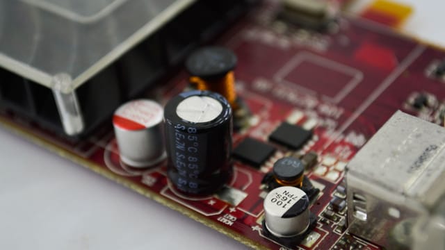Detailed macro shot of a circuit board highlighting capacitors, chips, and circuits.
