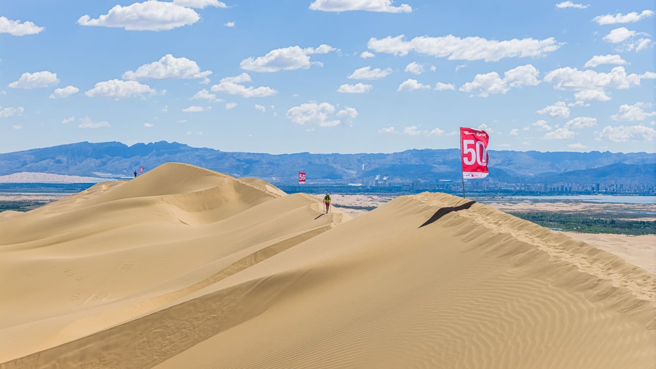 Vast desert landscape with sand dunes under a blue sky.