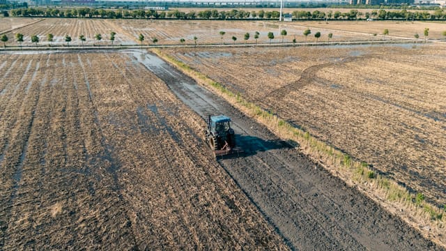 Aerial shot of a tractor plowing a wet field in Hangzhou, Zhejiang, China.