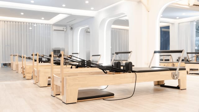 Spacious and minimalist pilates studio featuring wooden reformers for fitness workouts.