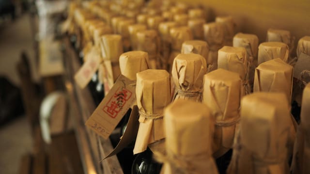 Close-up view of rustic bottles with brown paper wrapping in an artisanal setting.