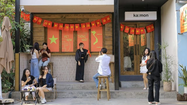 Colorful Vietnamese cafe exterior with festive banners and people socializing.