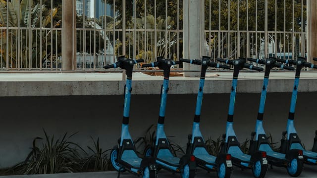 A line of blue electric scooters parked outdoors, reflecting modern urban mobility in Natal, Brazil.