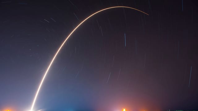 A breathtaking shot of a rocket launch, creating a vivid trail under a starry night sky.