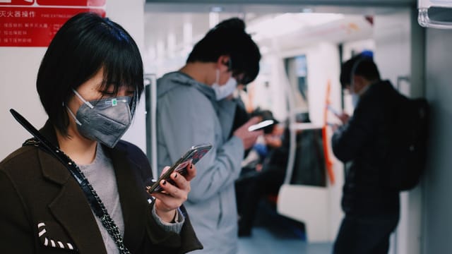 Adults wearing masks and using mobile phones on Shanghai subway amid COVID pandemic.