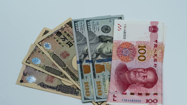 Various international currency notes including US dollars, yen, and yuan arranged on a surface.
