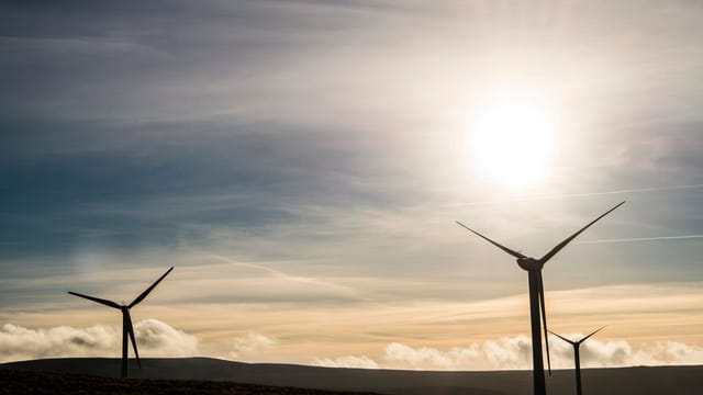 Silhouetted wind turbines generate renewable energy against a stunning sunrise sky.