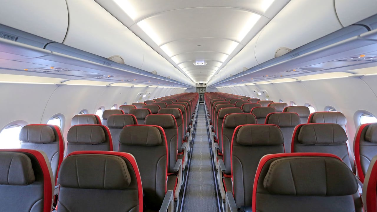 Wide view of an aircraft cabin with empty rows of seats, ready for boarding.