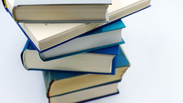 A pile of books with blue covers on a white background, symbolizing education and knowledge.