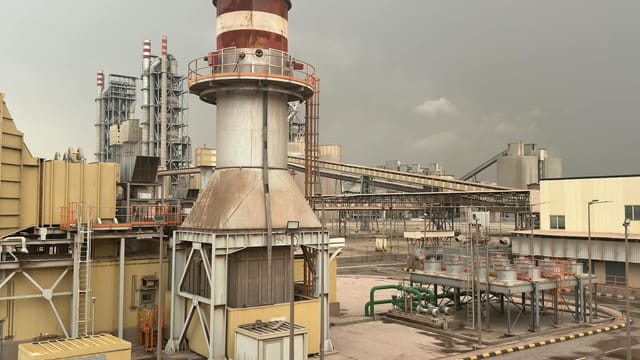 A large industrial facility on a cloudy day in Saudi Arabia, showcasing structures and machinery.