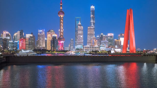 Explore the vibrant Shanghai skyline lit up at night, featuring iconic buildings and reflections on the river.