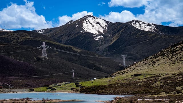 Breathtaking view of snow-capped mountains in Sichuan, China, with power lines crossing the serene landscape.