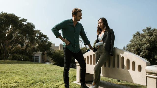 A couple in a tense discussion in a park setting, conveying relationship conflict.