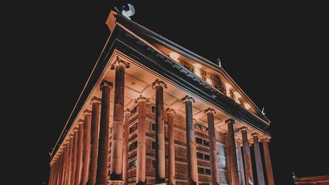 Illuminated architectural landmark at night with neoclassical design and grand pillars.