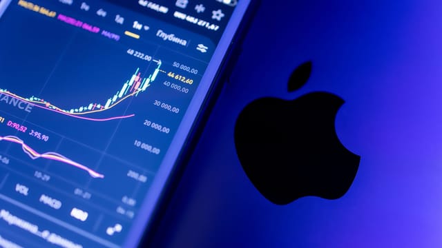 A close-up of an Apple device displaying stock market graphs, indicating economic trends.