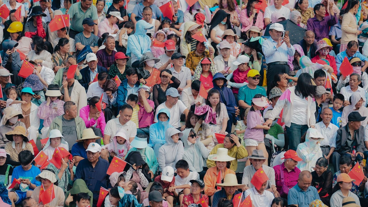 A densely packed crowd with flowers and flags fills a vibrant stadium, exuding excitement.