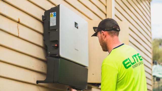 A skilled technician working on the installation of a solar inverter system outdoors. Energy efficiency solution.