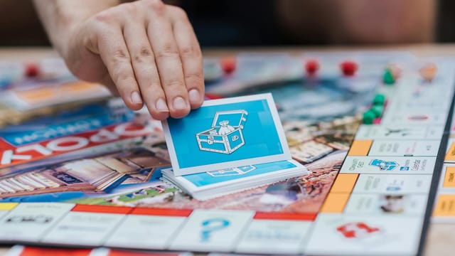 A close-up shot of a hand picking a card during a Monopoly board game session.
