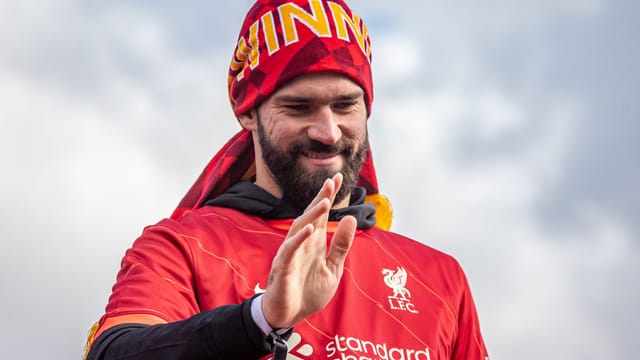 Liverpool FC player joyfully celebrates victory under the clear sky.