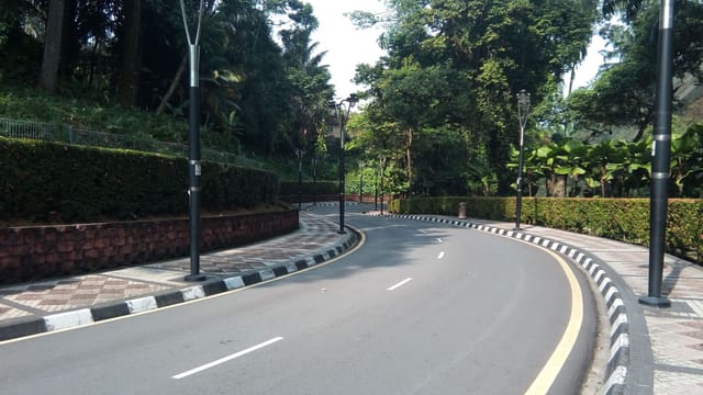 A scenic curved road lined with street lamps and greenery in Kuala Lumpur, Malaysia.