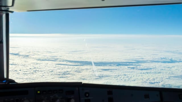 Experience the serene beauty of fluffy clouds from an airplane cockpit high above the sky.