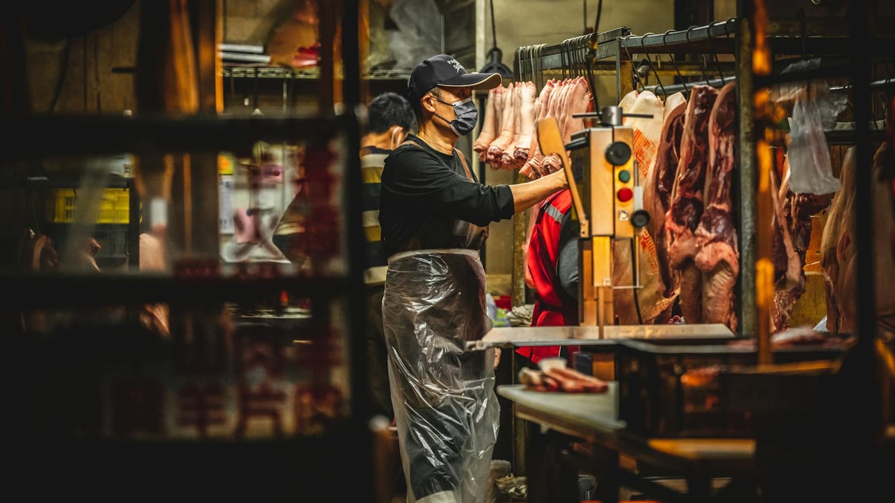 Butchers working in a Miaoli, Taiwan meat market, handling fresh pork.