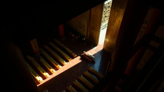 A serene view of a temple interior in Shanghai with sunlight creating dramatic patterns on the floor.
