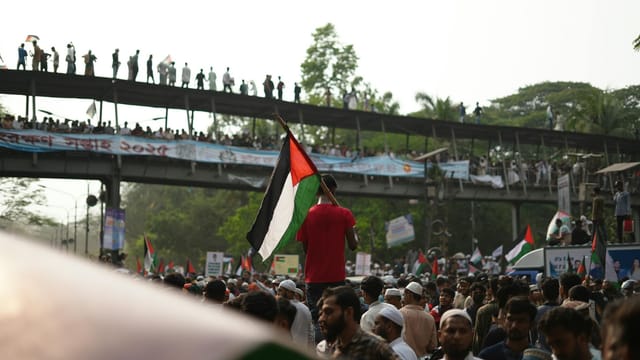 Large crowd in Dhaka rallying with Palestinian flags during a pro-Palestine protest.