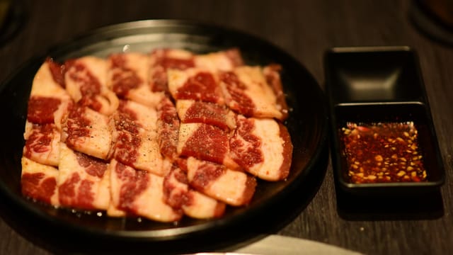 Juicy marbled beef slices with a rich seasoning sauce, ready for grilling.