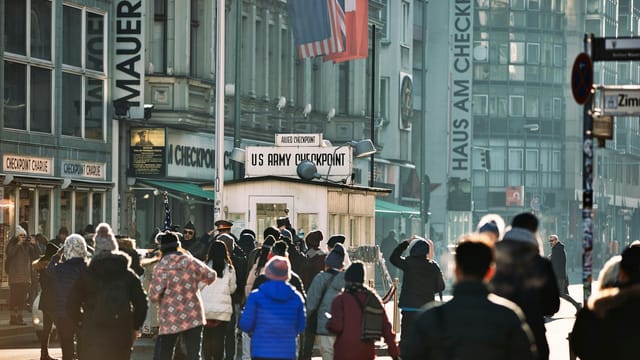 Crowd of tourists gathered at the historic Checkpoint Charlie in Berlin, Germany.