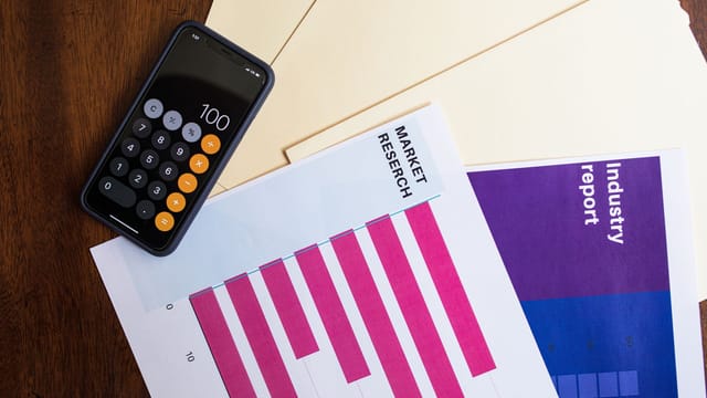 Flat lay of smartphone and market research papers on wooden table for business analysis.