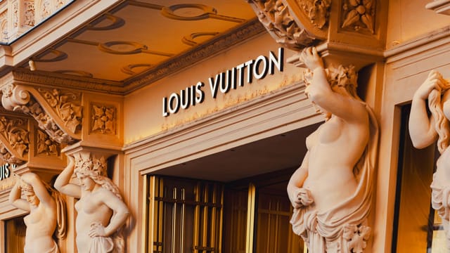 Grand facade of Louis Vuitton store featuring ornate sculptures in Vienna's shopping district.
