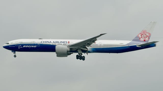 Side view of a China Airlines Boeing 777 airplane flying against a cloudy sky.