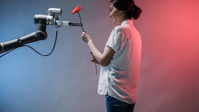 A woman interacts with a robotic arm holding a flower, showcasing technology and human connection.