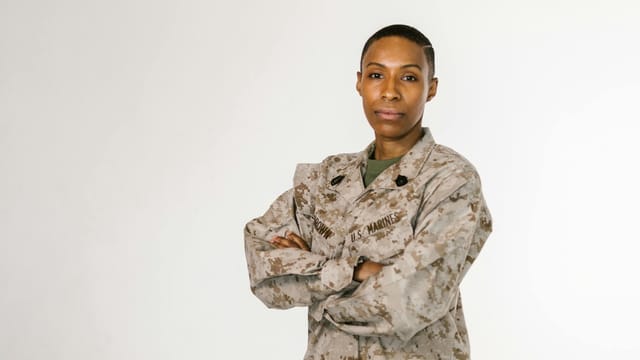 Portrait of a female African American soldier in a US Marines uniform on a white background.
