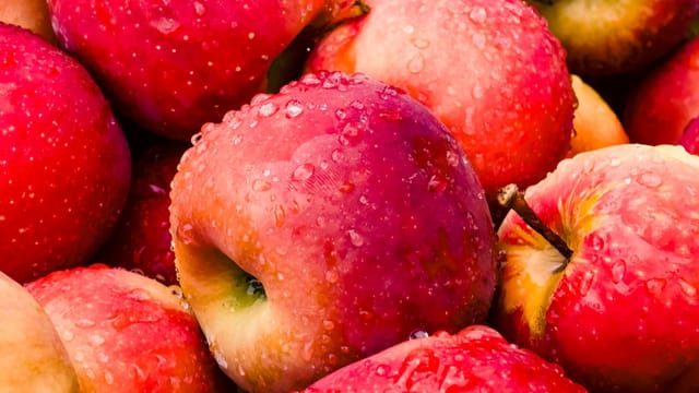 Close-up of vibrant red apples covered in water droplets, showcasing freshness.