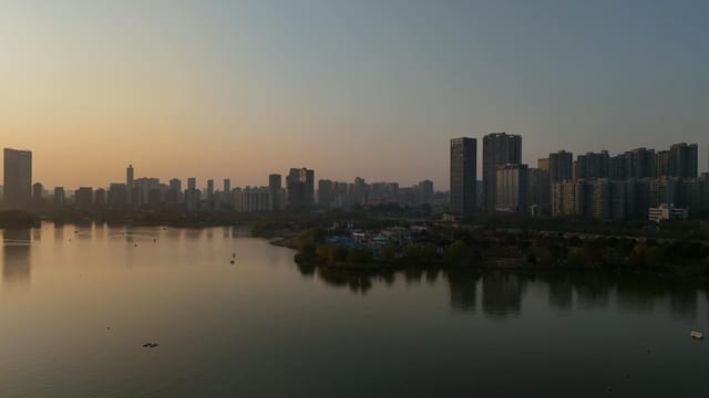 Scenic aerial view of Changsha city skyline with tranquil river at sunset.