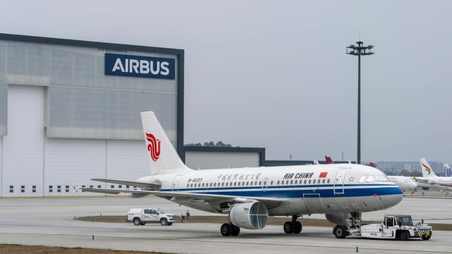 Air China Airbus A320 parked at Airbus hangar, showcasing aviation industry infrastructure.