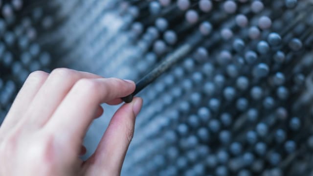 A hand interacts with a metallic art installation, showcasing texture and depth.
