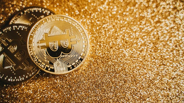 Close-up of bitcoins on a shimmering gold background, symbolizing digital wealth and investment.