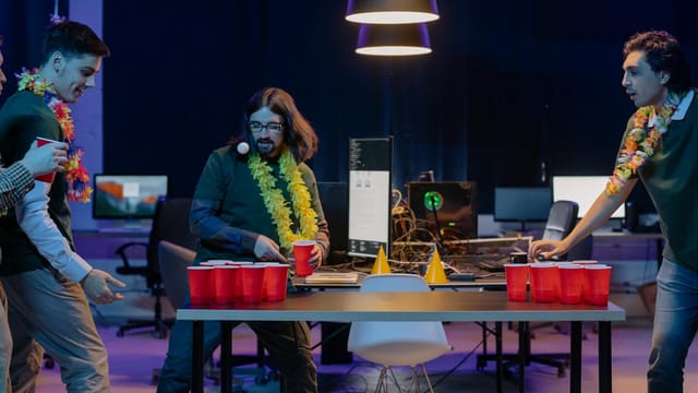 A group of men enjoying a lively beer pong game indoors with vibrant decor and red cups.