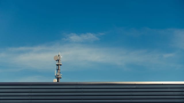 A modern telecommunication tower stands against a clear blue sky, showcasing technological advancement.