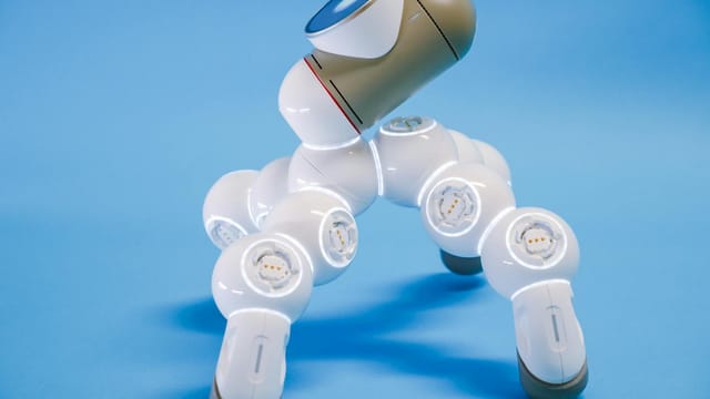 A close-up view of a futuristic robotic device against a blue background.