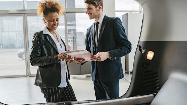 Dealer discussing vehicle options with a client inside a modern car showroom.