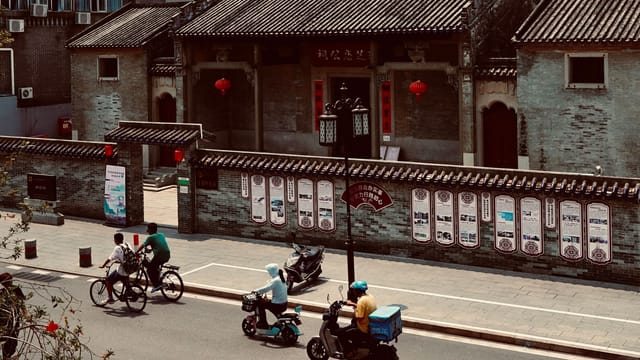 Bicycles and scooters travel past historical architecture on a city street in Zhu Hai Shi, China.