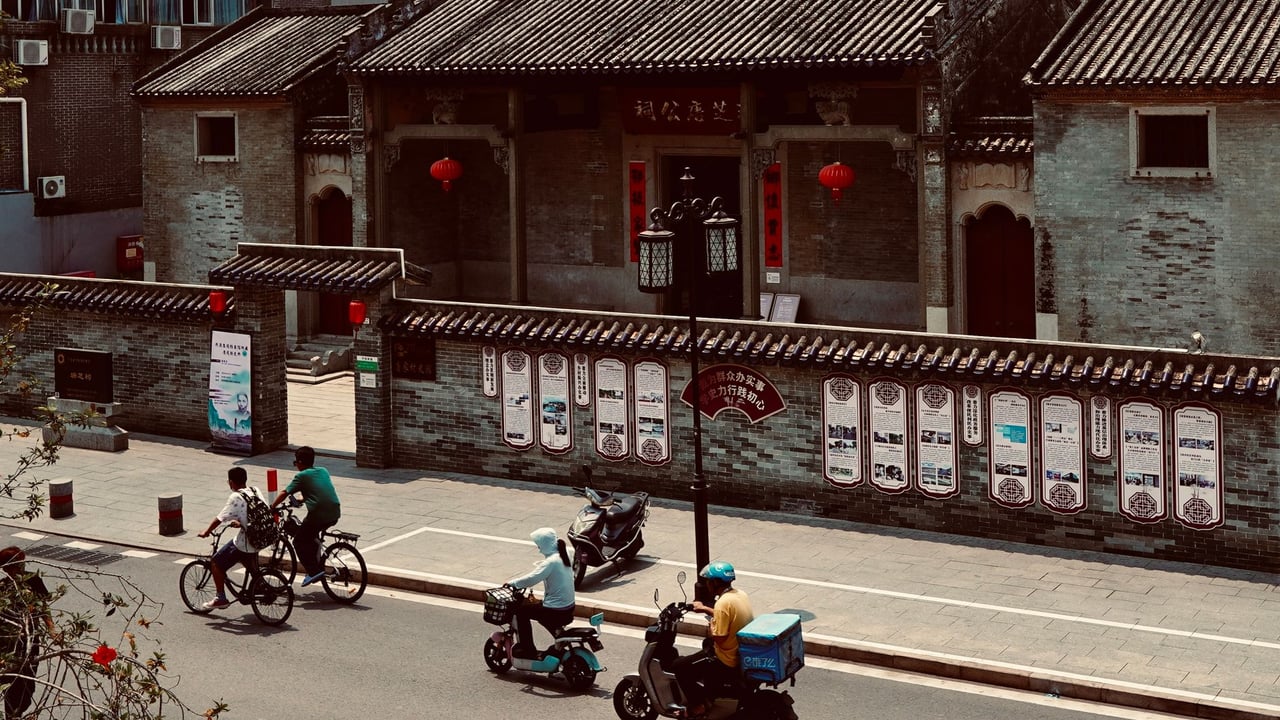 Bicycles and scooters travel past historical architecture on a city street in Zhu Hai Shi, China.