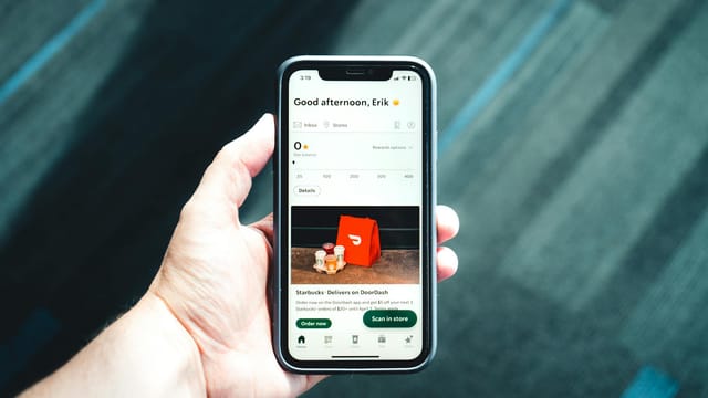 Close-up of a smartphone with a delivery app interface in a person's hand, emphasizing modern e-commerce.